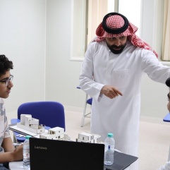 Saudi teacher explaining to two students at The Academic Talent Enrichment Program.